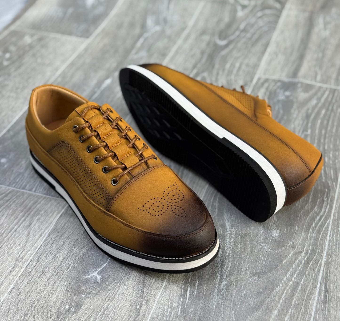 chaussures de ville basses en cuir marron avec des perforations et une semelle blanche.