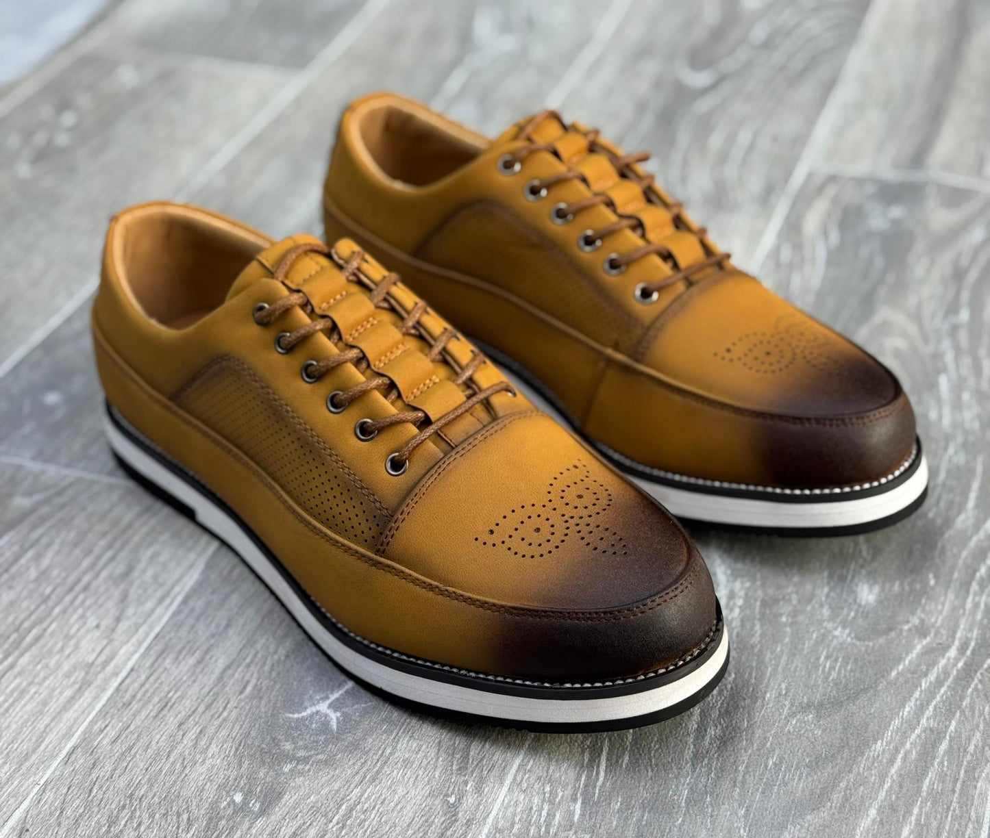 chaussures de ville basses en cuir marron avec des perforations et une semelle blanche.