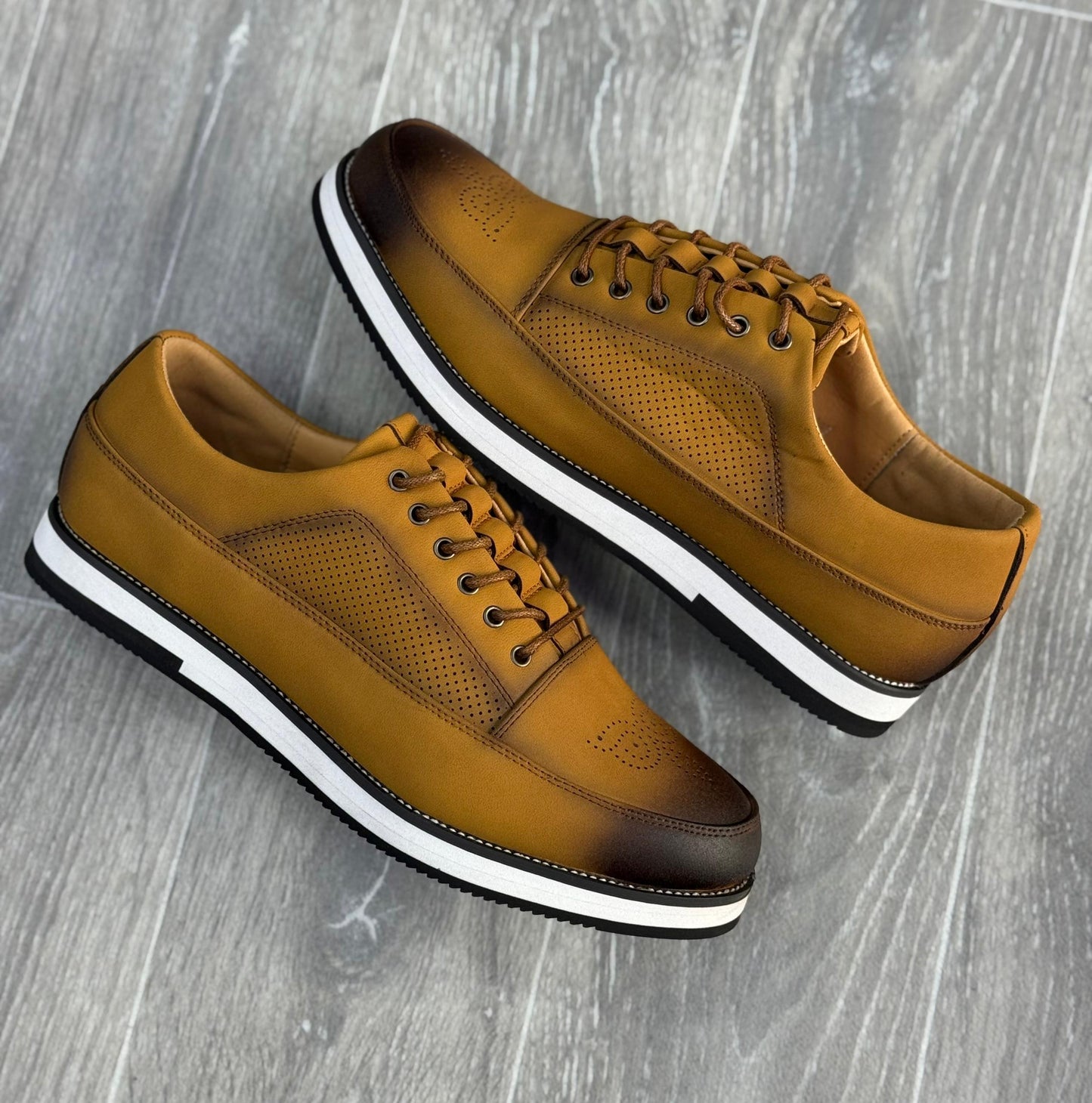 chaussures de ville basses en cuir marron avec des perforations et une semelle blanche.